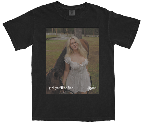 Washed black t-shirt featuring the official 'girl, you'll be fine' single cover art by Micks. The design includes the song title and desert-inspired imagery.